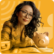 A woman with long hair and glasses is seated at a table, writing in a notebook. She is shown with a slight smile, wearing a yellow checkered blazer that speaks of her entrepreneurial spirit. A pink piggy bank is placed near her, hinting at her business ideas for women. The background is an artistic yellow pattern.