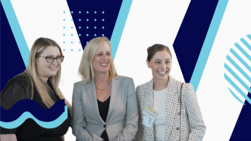 Three women are standing together in front of a stylized background with blue and white patterns. The woman on the left has long hair and glasses, the middle woman is in a gray blazer, and the woman on the right has her hair pulled back and is wearing a white jacket. They are all smiling, exemplifying women in business.